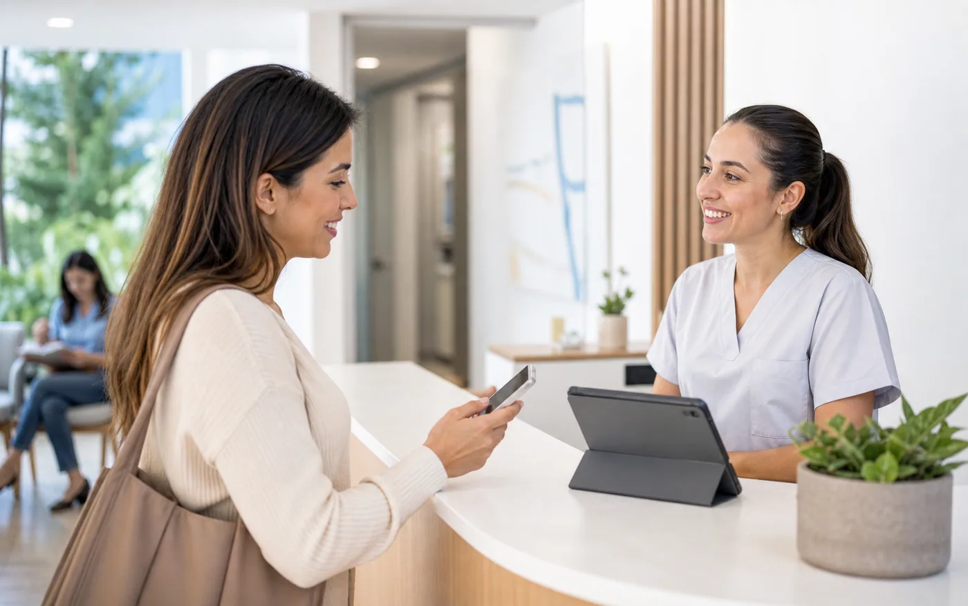 Recepción de clínica luminosa con personal sanitario atendiendo a una paciente con smartphone
